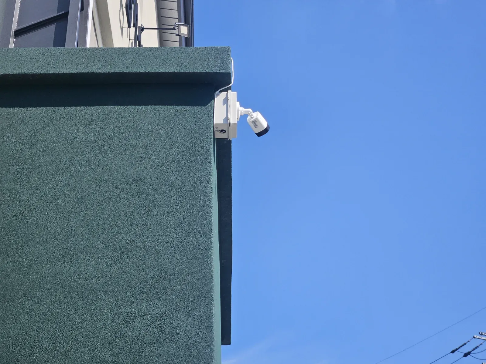 파란 하늘 아래 펜션 외벽에 설치된 CCTV 카메라