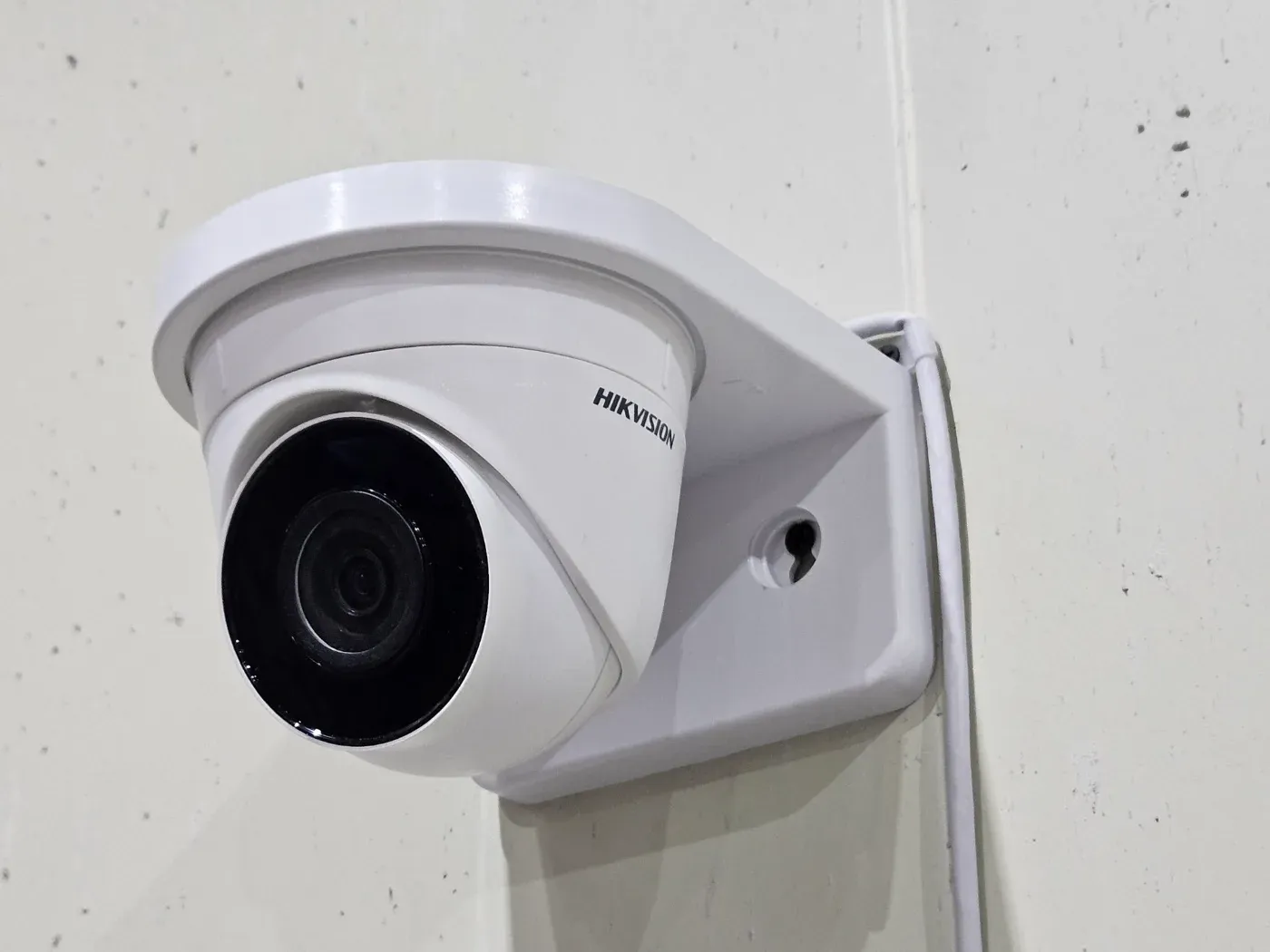 흰 벽에 설치된 돔형 CCTV 카메라 클로즈업