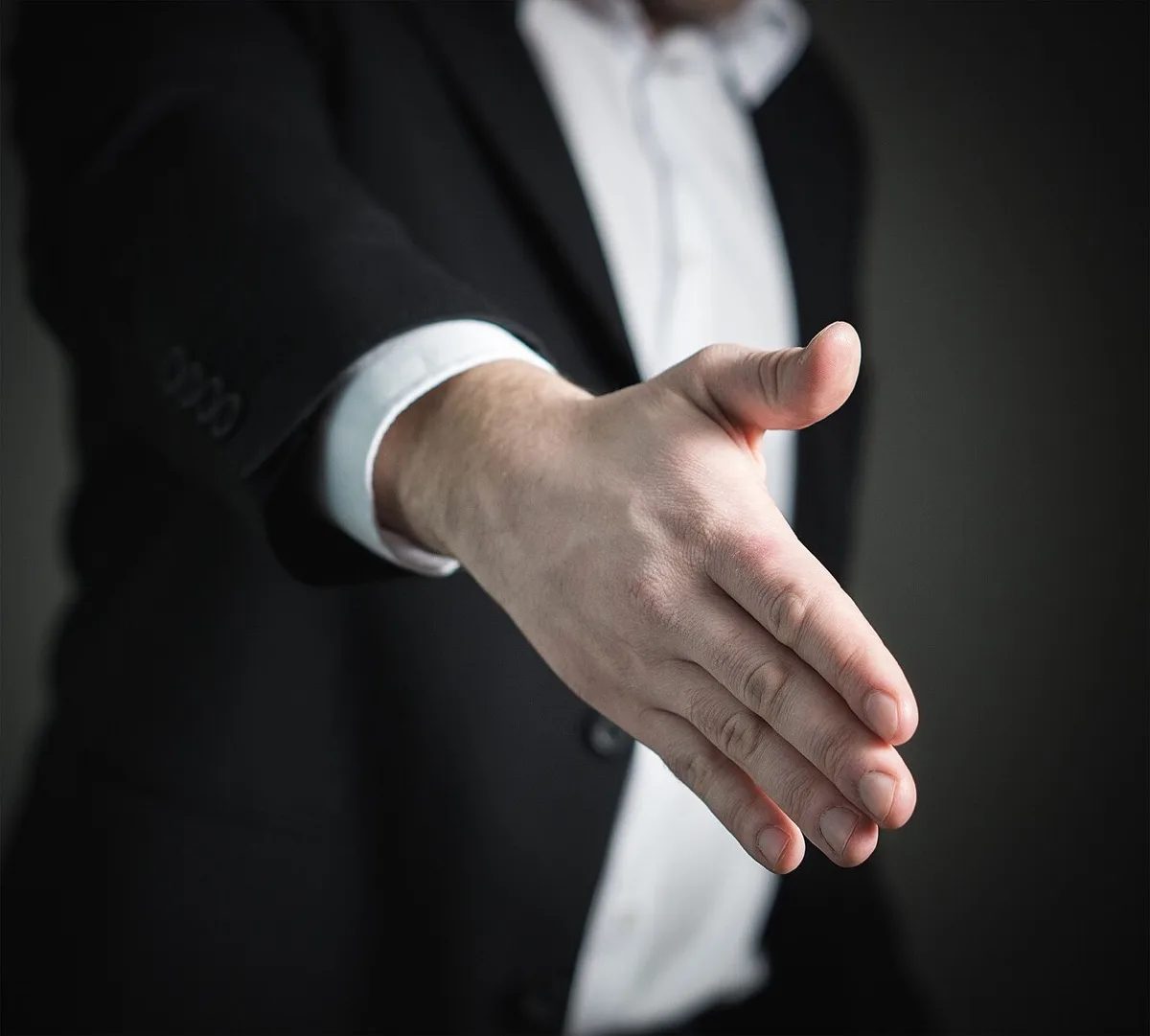 악수를 청하며 손을 내민 정장 차림의 남성